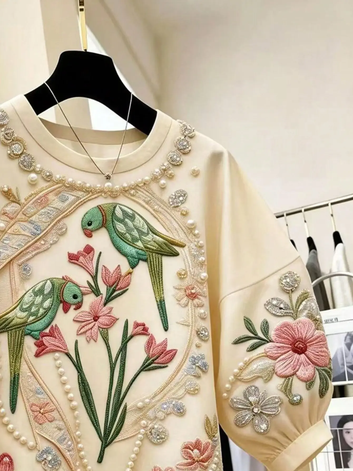 Close-up of bird and floral embroidery on cream top