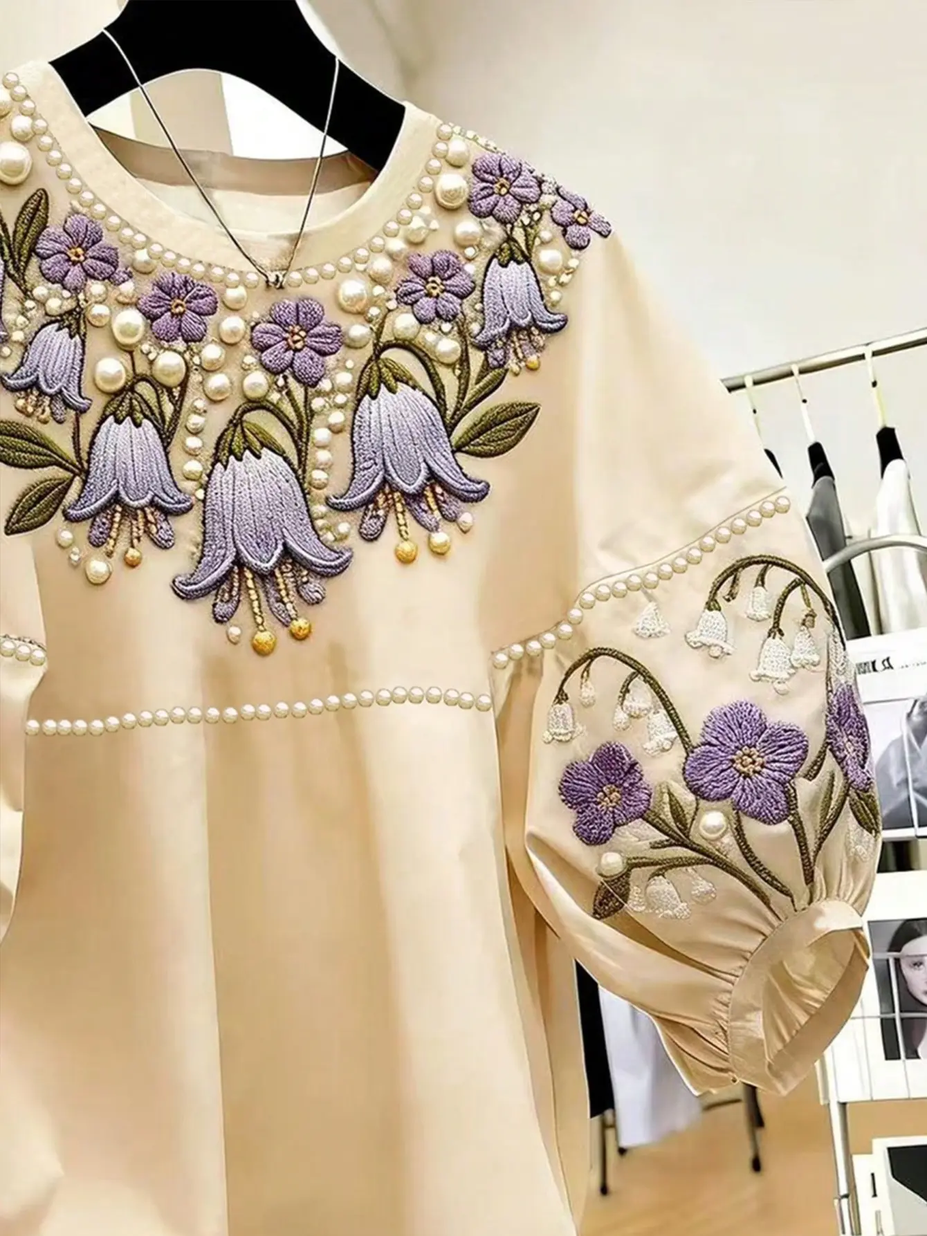 Close-up of purple floral embroidery on cream top