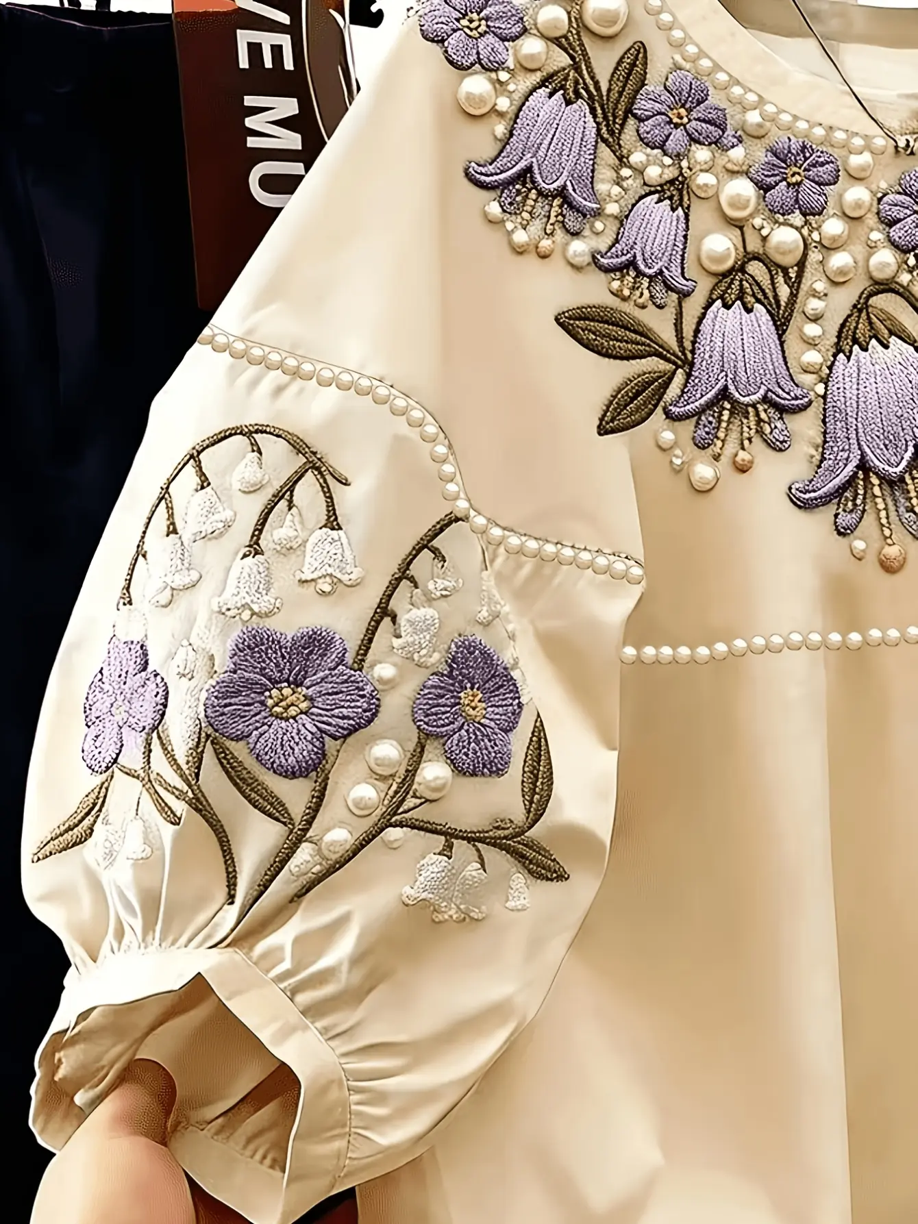 Close-up of embroidered petal sleeve on cream top