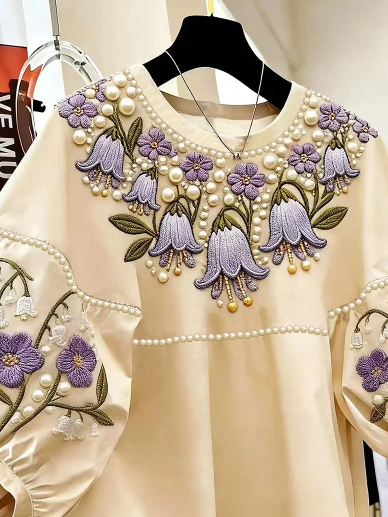Close-up of purple floral embroidery on cream top