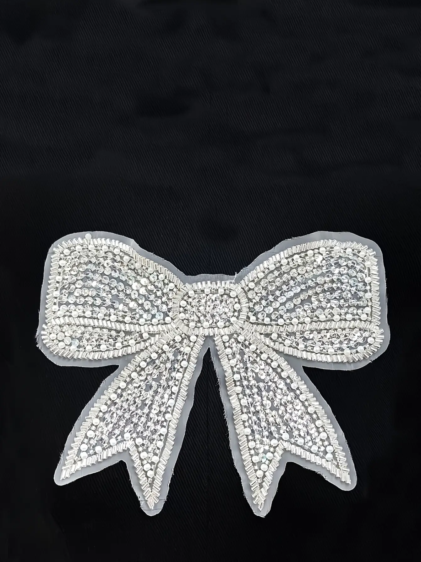 Close-up of silver beaded bow applique on black T-shirt