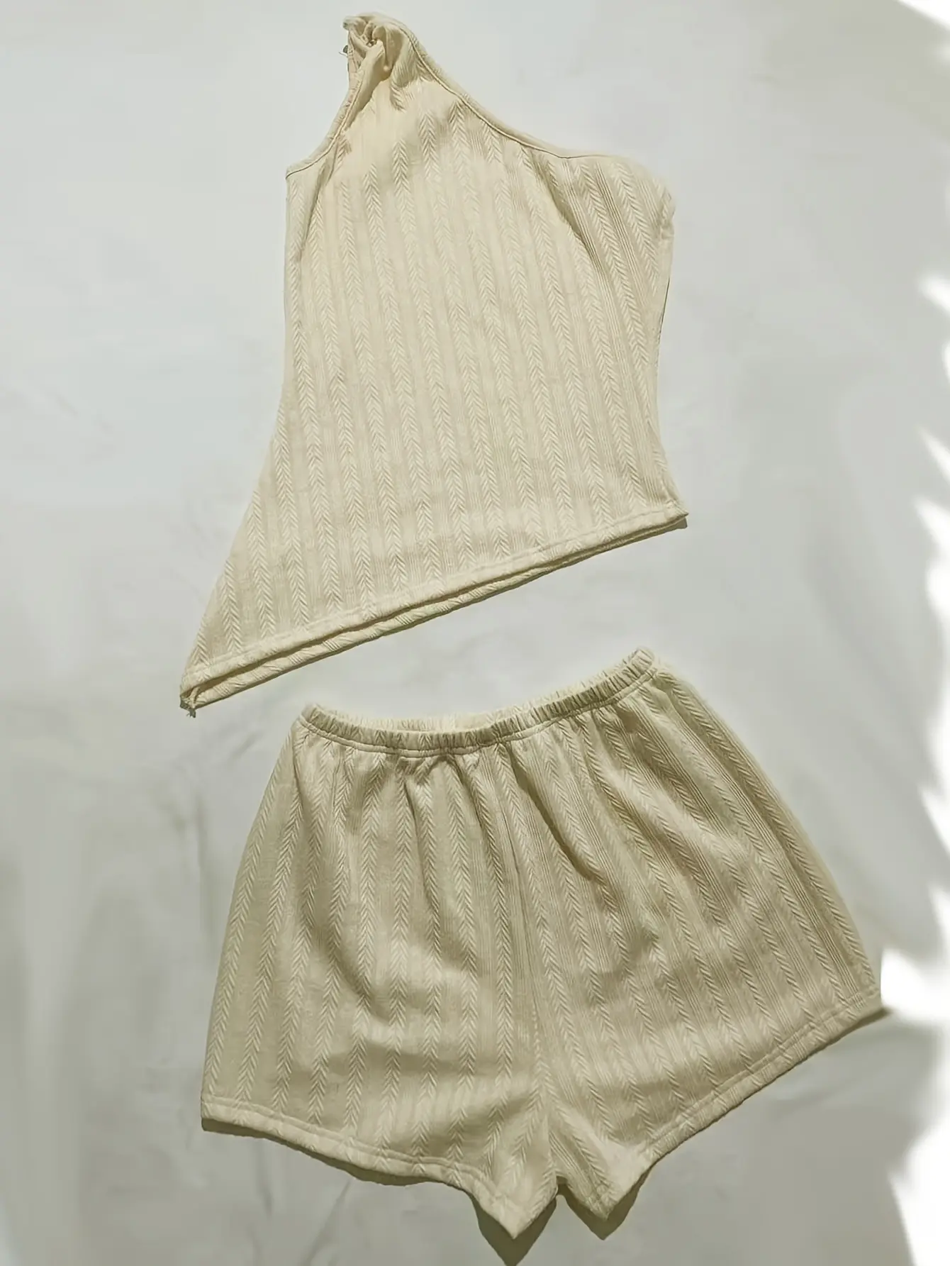 Cream one-shoulder knit top and shorts set laid flat