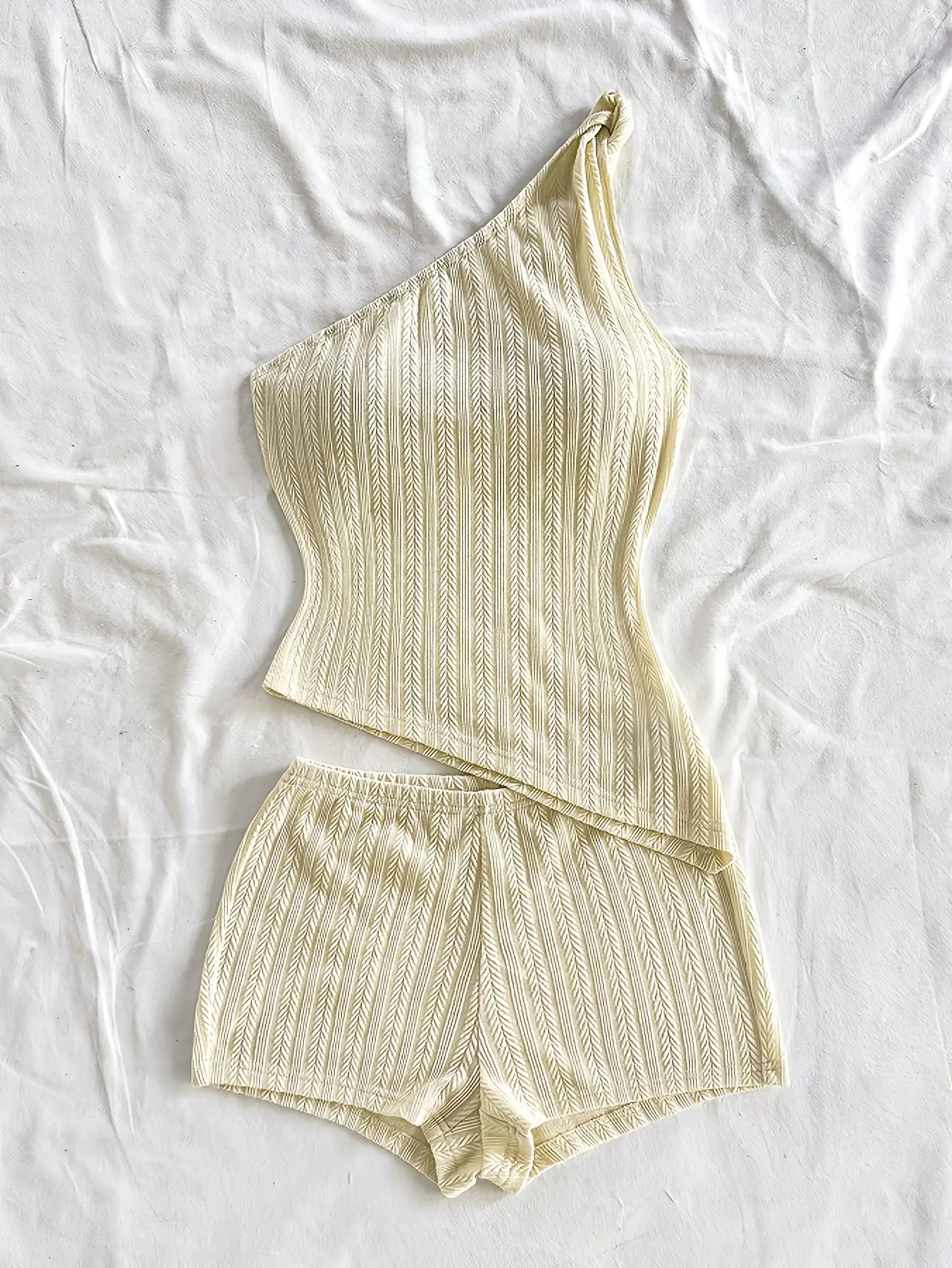 Cream one-shoulder knit top and shorts set laid flat