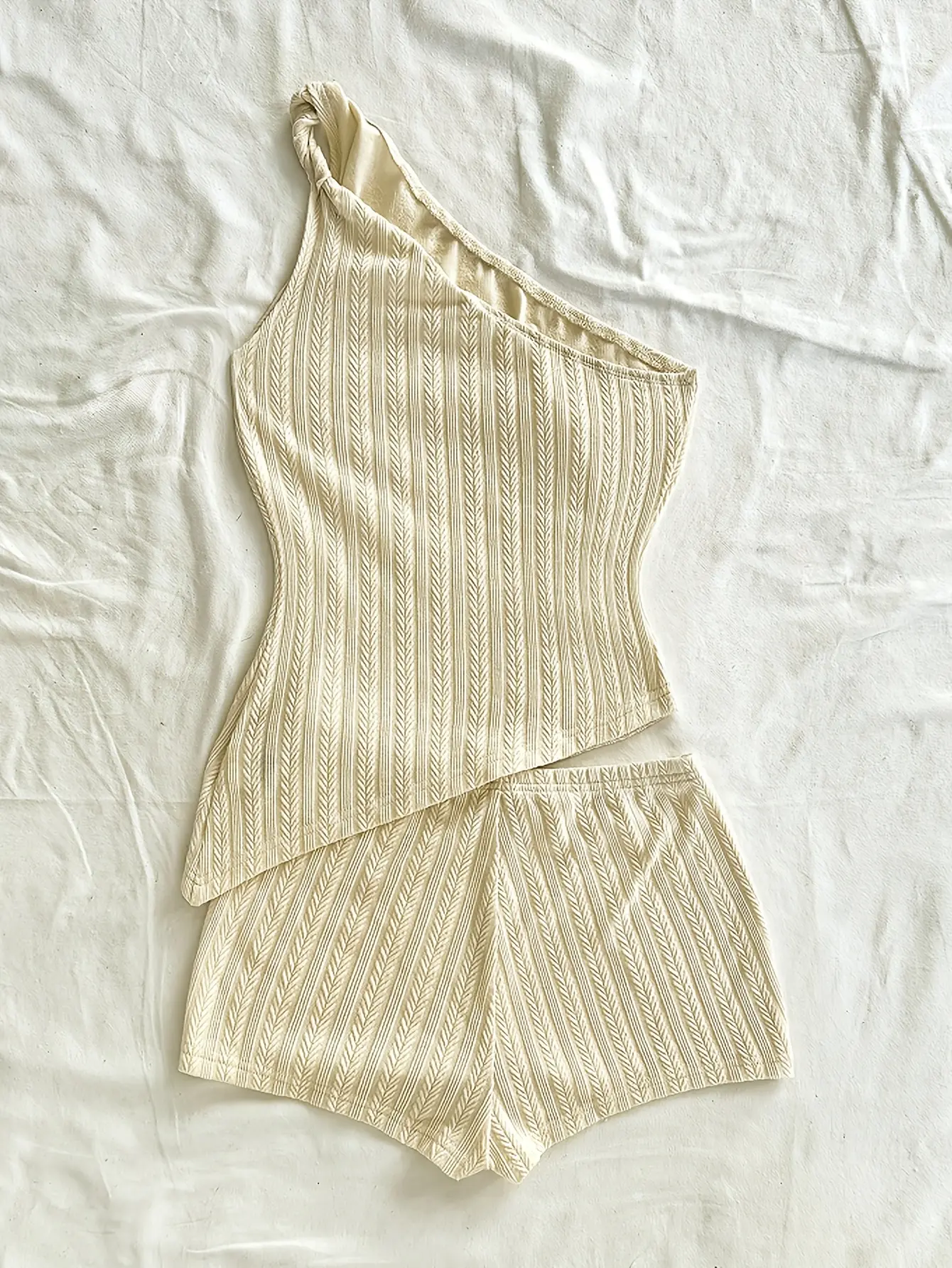Cream one-shoulder knit top and shorts set laid flat