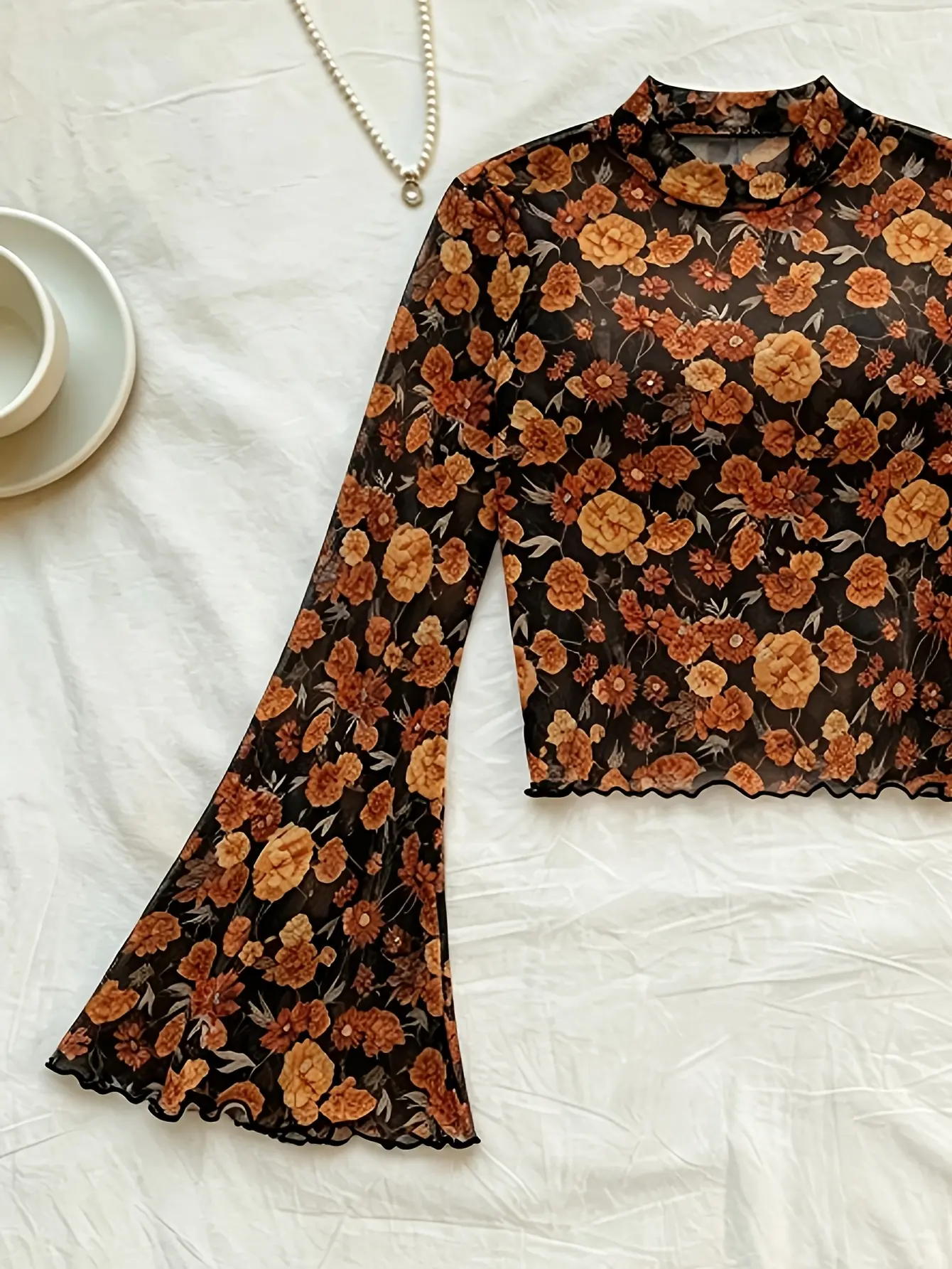 Black floral mock-neck bell-sleeve mesh top laid flat