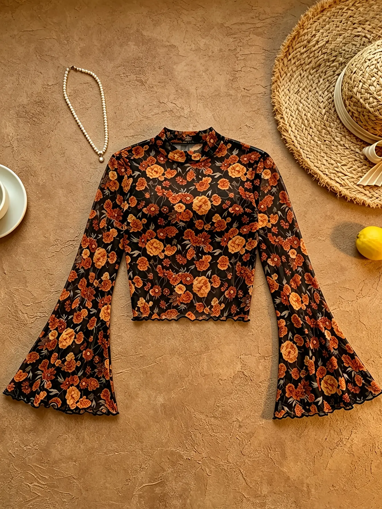 Black floral mock-neck bell-sleeve mesh top laid flat