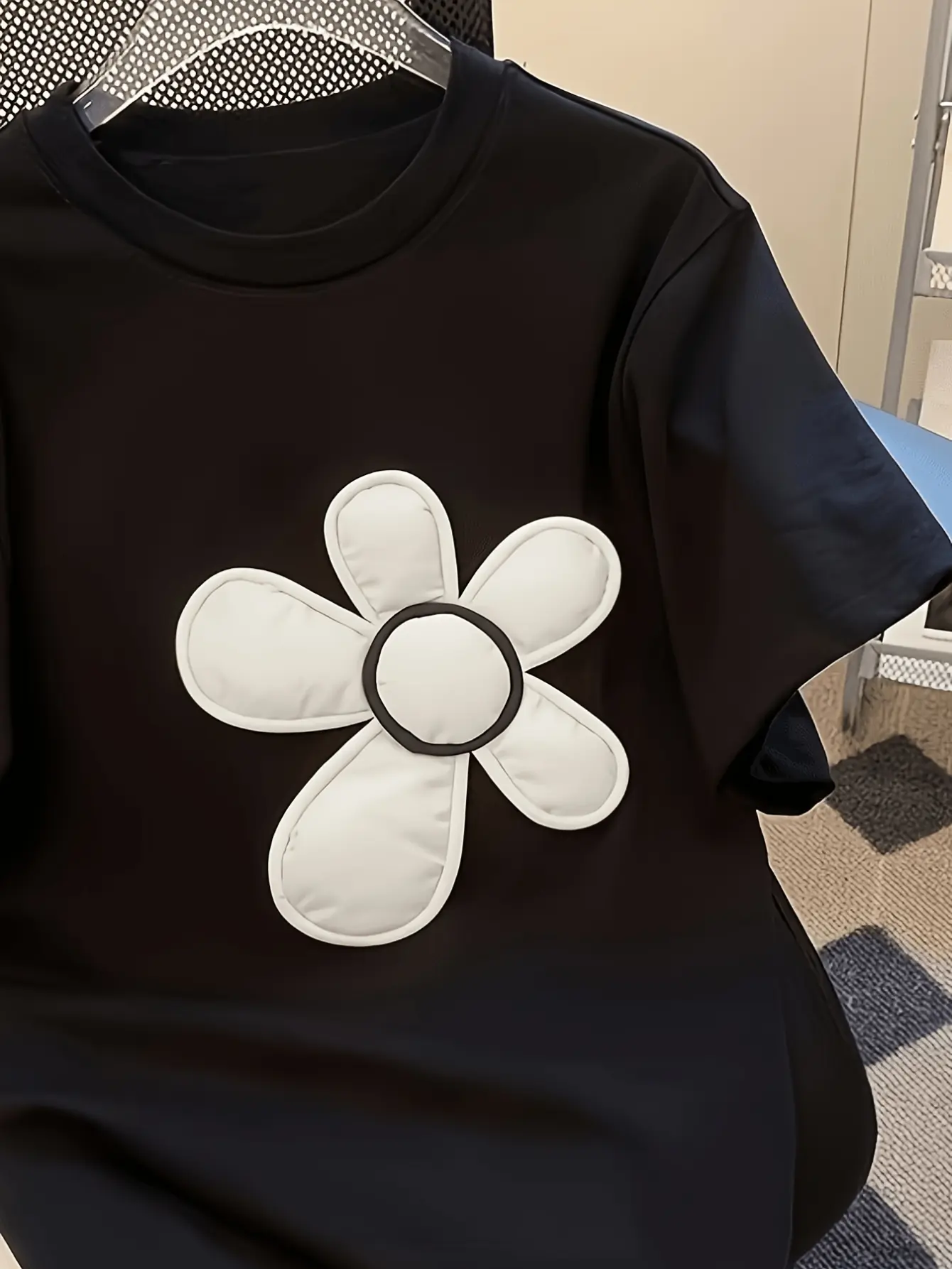 Black crew-neck top with white flower applique