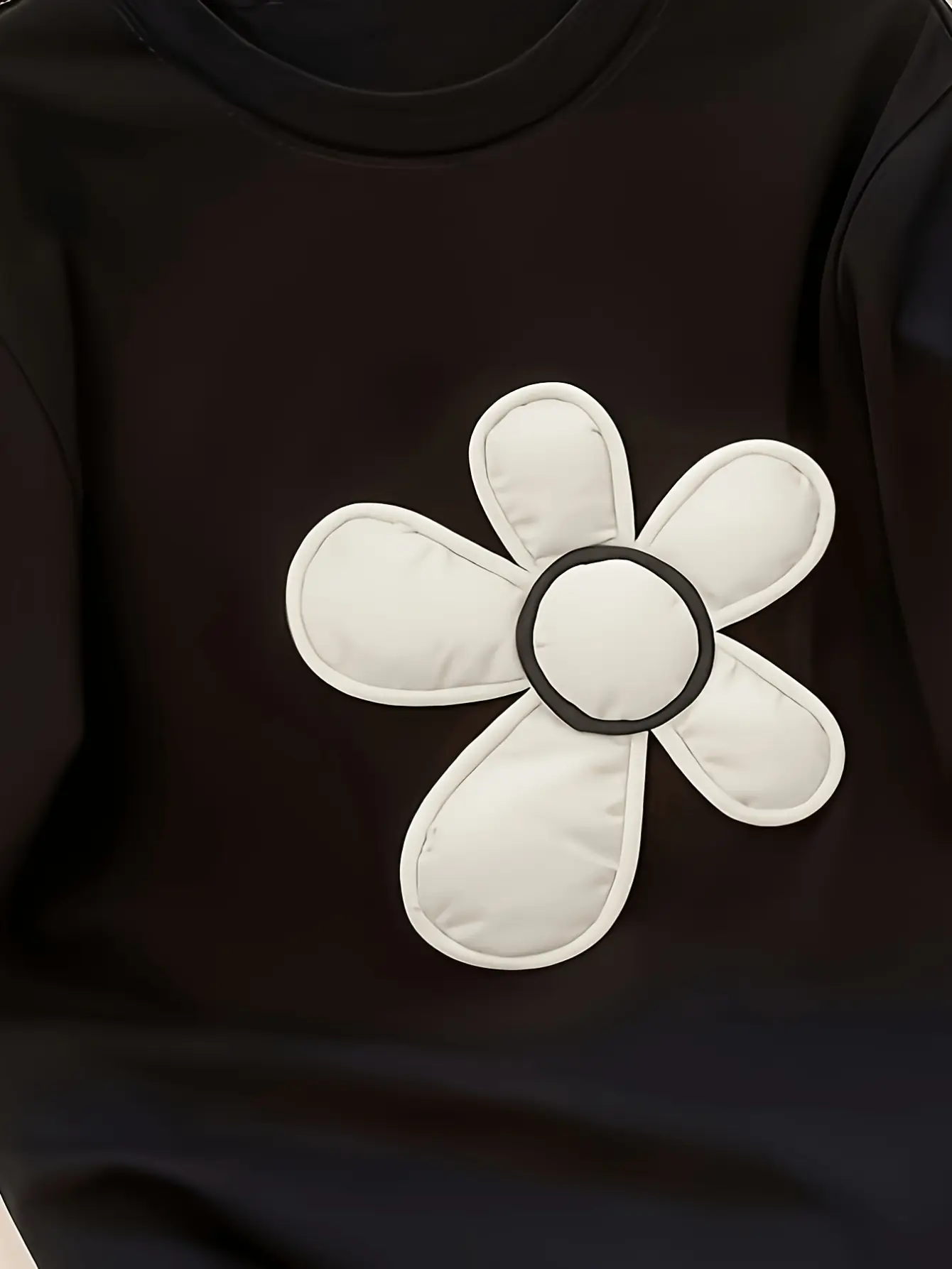 Close-up of white flower applique on black top